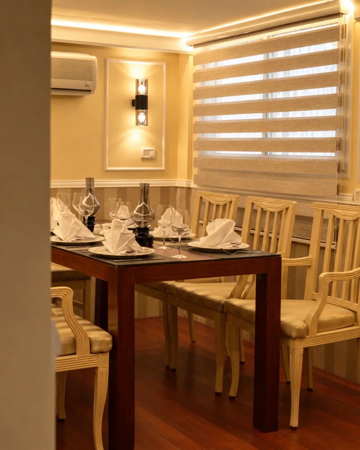 Le petit salon, table d'acajou et appliques, stores baissés.